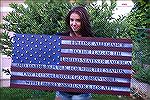 Girl holding nice wooden U.S. flag with pledge of allegiance.